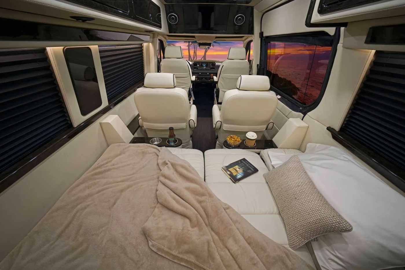 Sprinter camper interior with a made bed and forward lounge seating