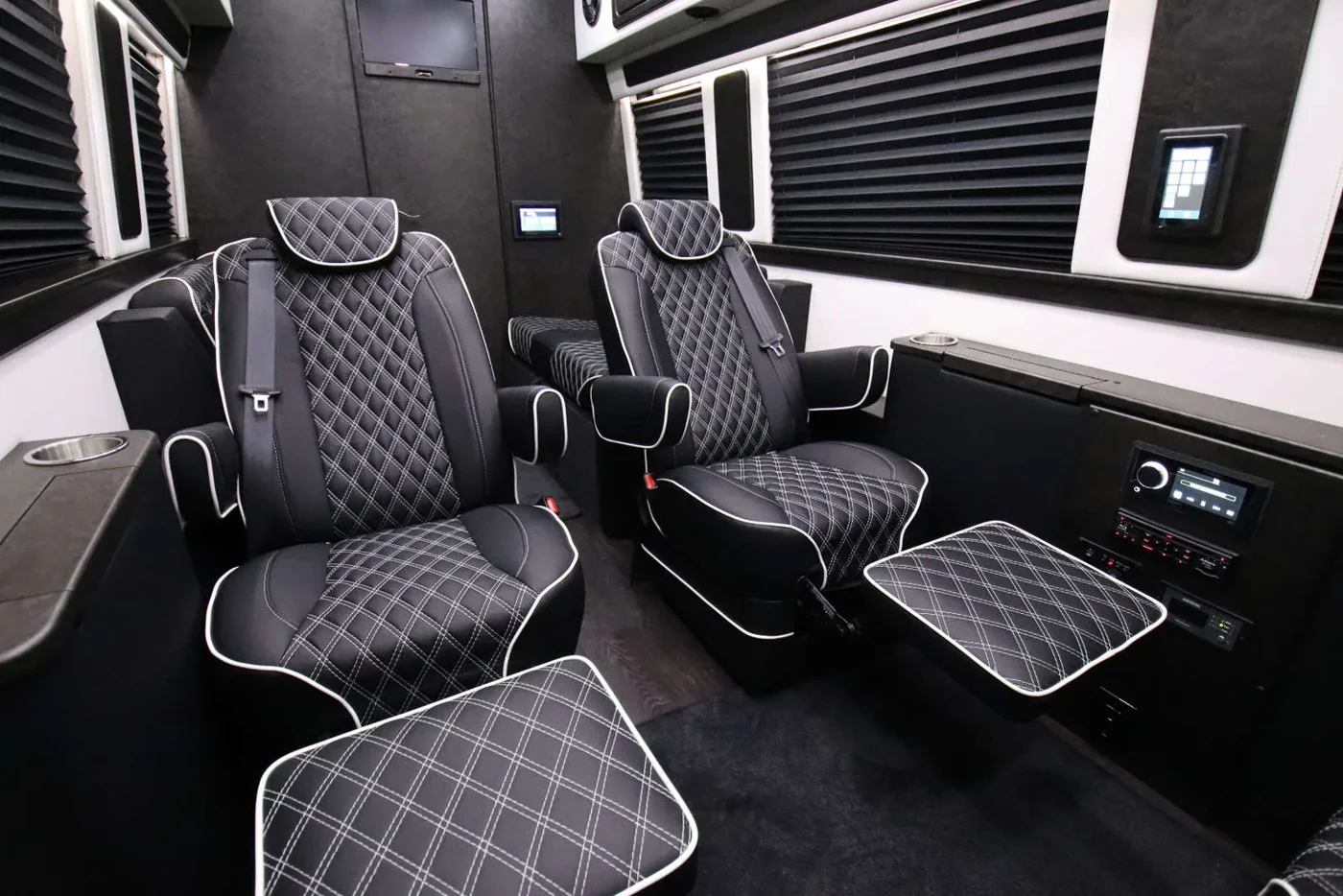 Quilted black captain’s chairs in a luxury Sprinter cabin