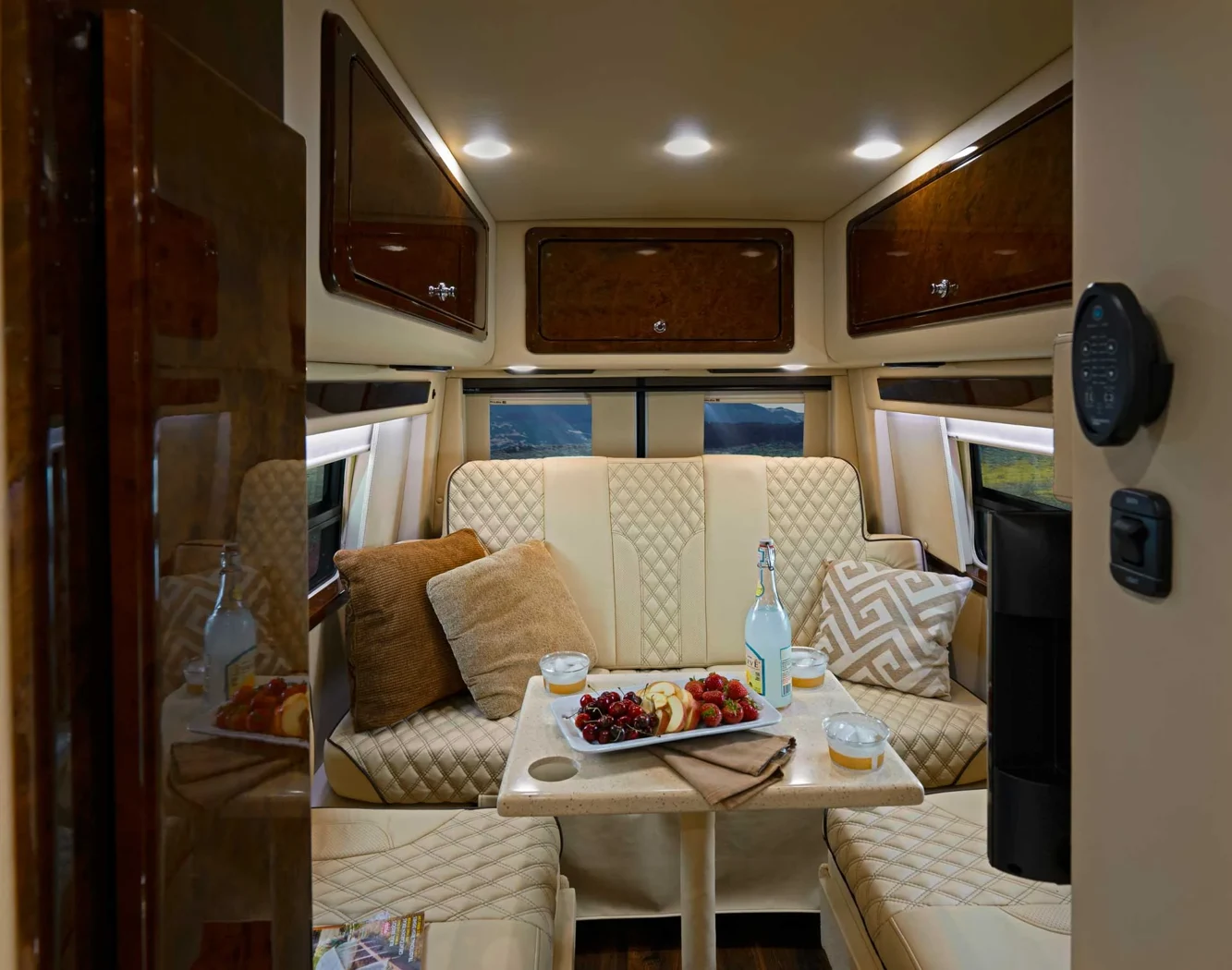 Sprinter camper lounge with cream upholstery, cabinetry and a dining table