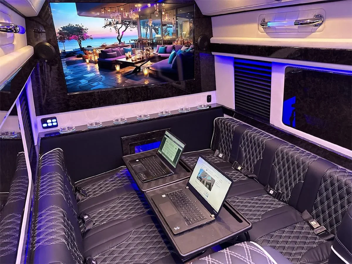 Luxury Sprinter cabin with a large display and laptop on a folding table