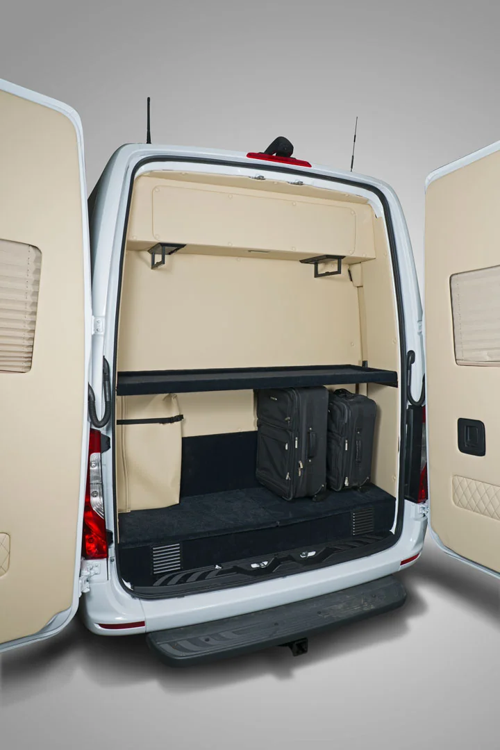Open rear luggage compartment of a Sprinter with two upright suitcases