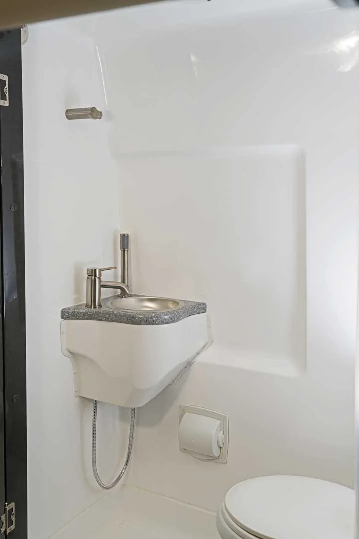 Sprinter wet bathroom with a small sink, shower hose and toilet